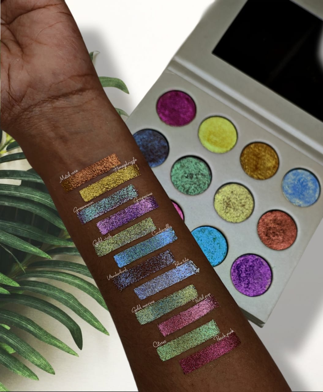 Glitter Galaxy multichrome foiled eyeshadow palette with vibrant glitter and shimmer arm swatches on deep skin tone.