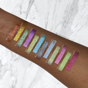Glitter Galaxy Cosmetics foiled eyeshadow swatches displayed on skin featuring metallic shimmer shades in bronze, gold, mint, lavender, aqua, blue, champagne, pink, and green with reflective foiled finishes.